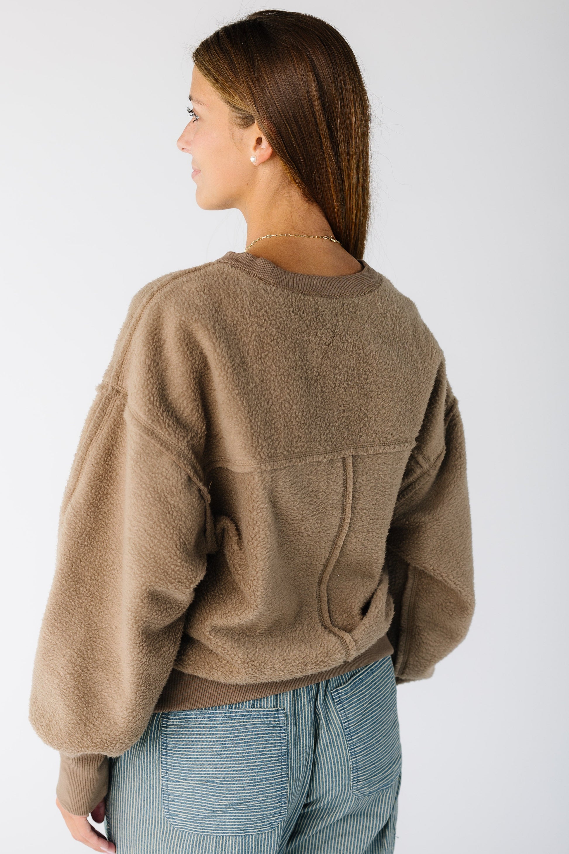 Back view of a woman wearing a fleece reversible sweatshirt with exposed seams