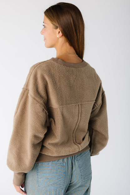 Back view of a woman wearing a fleece reversible sweatshirt with exposed seams