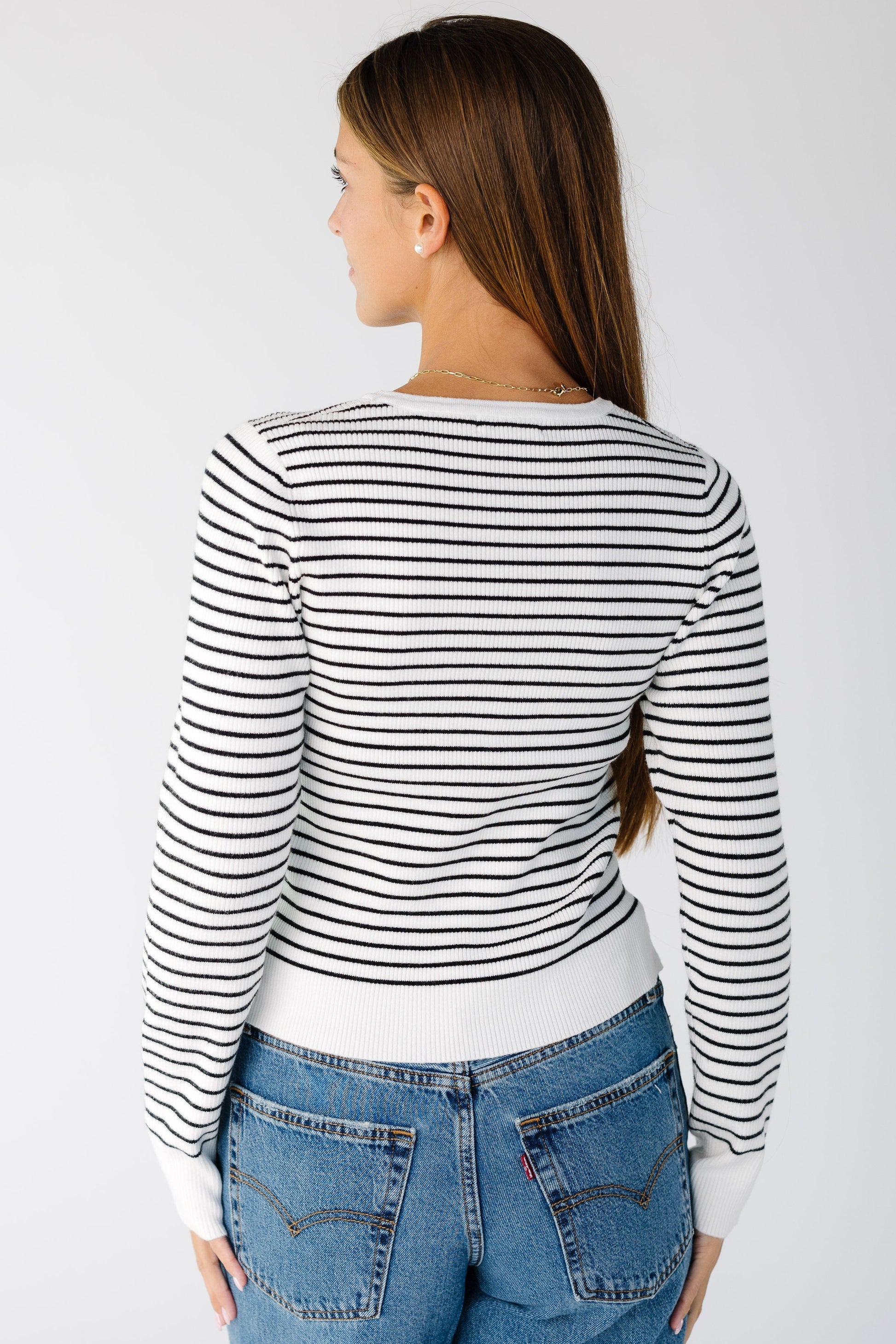 Back view of a woman wearing a white and black stripe sweater with long sleeves