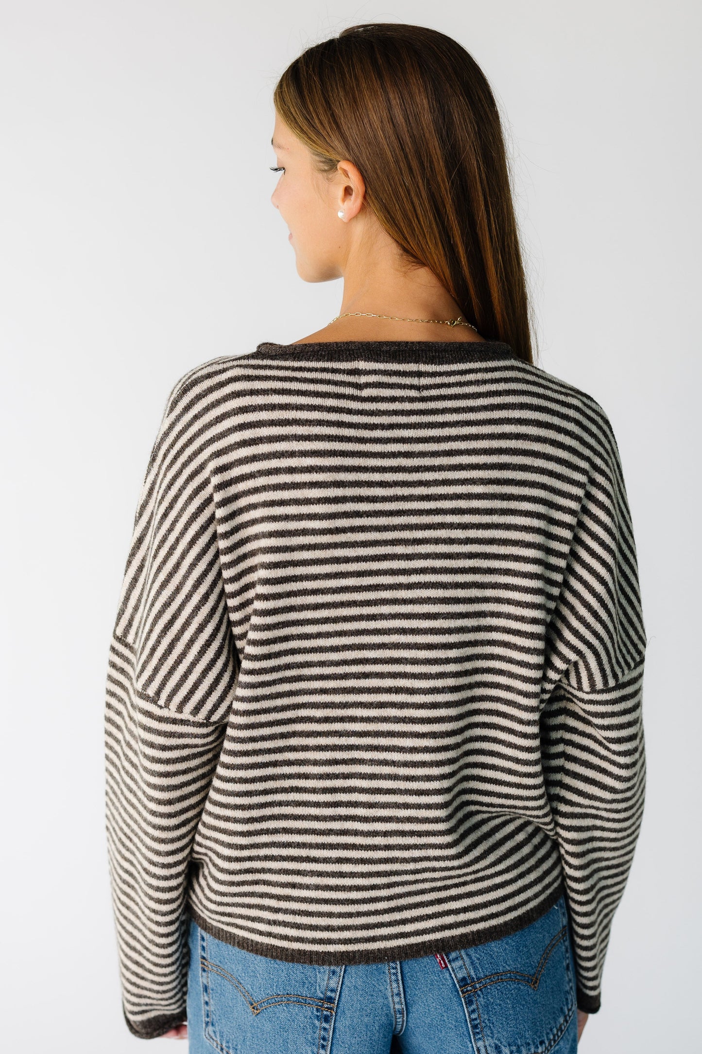 Back view of a woman wearing a brown stripe cardigan with long sleeves