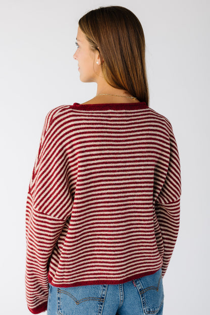 Back view of a woman wearing a dark red stripe cardigan with drop shoulders and long sleeves