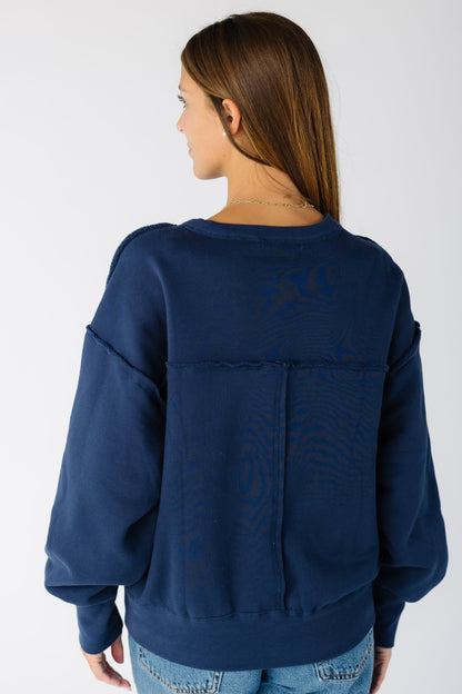 Back view of a woman wearing a navy sweatshirt with exposed seams