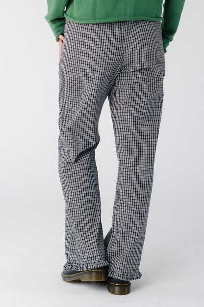 Back view of a woman wearing a pair of black and white plaid pants with a ruffle hem
