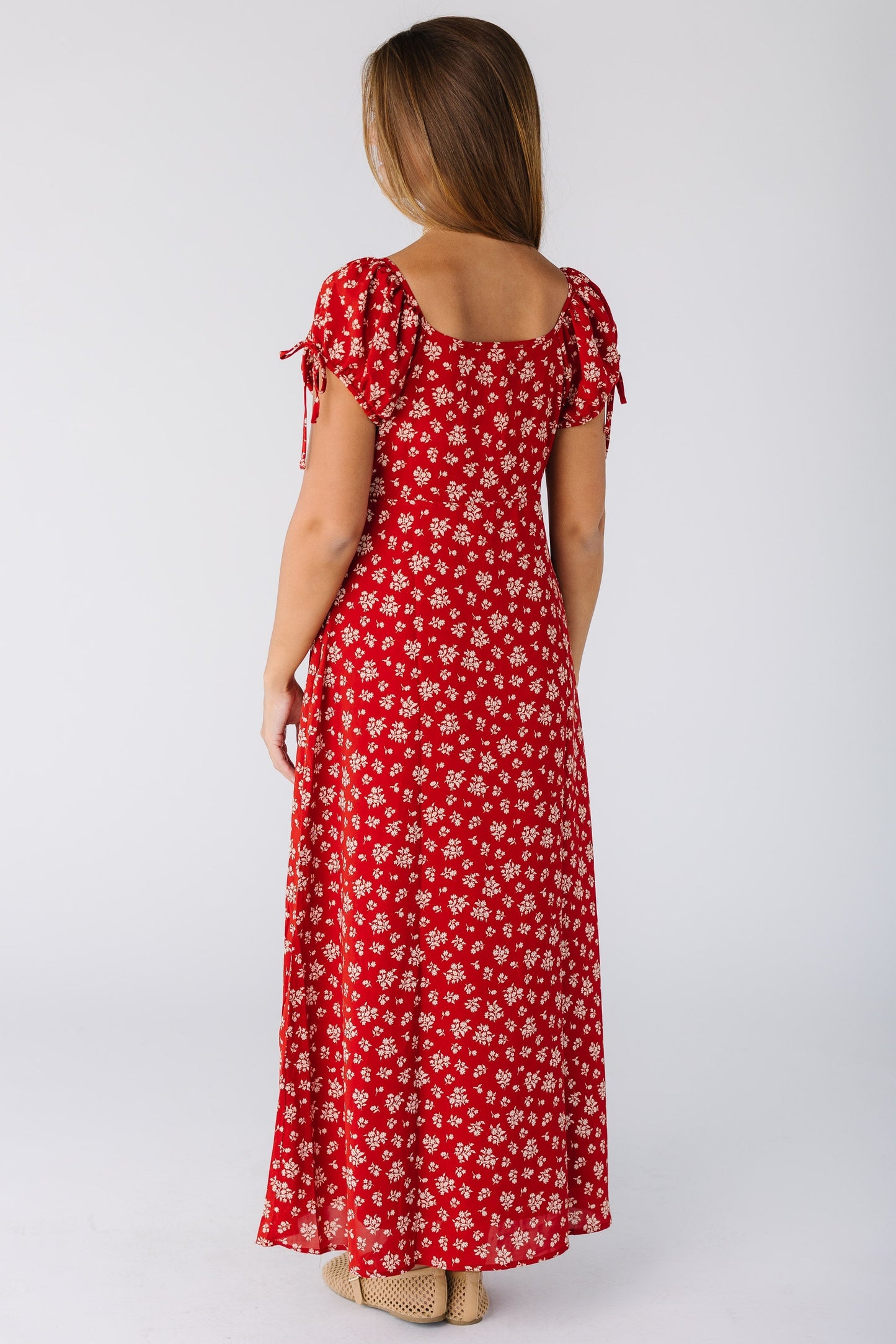 Back view of a woman wearing a red print maxi dress with square back neckline and short sleeves with ties