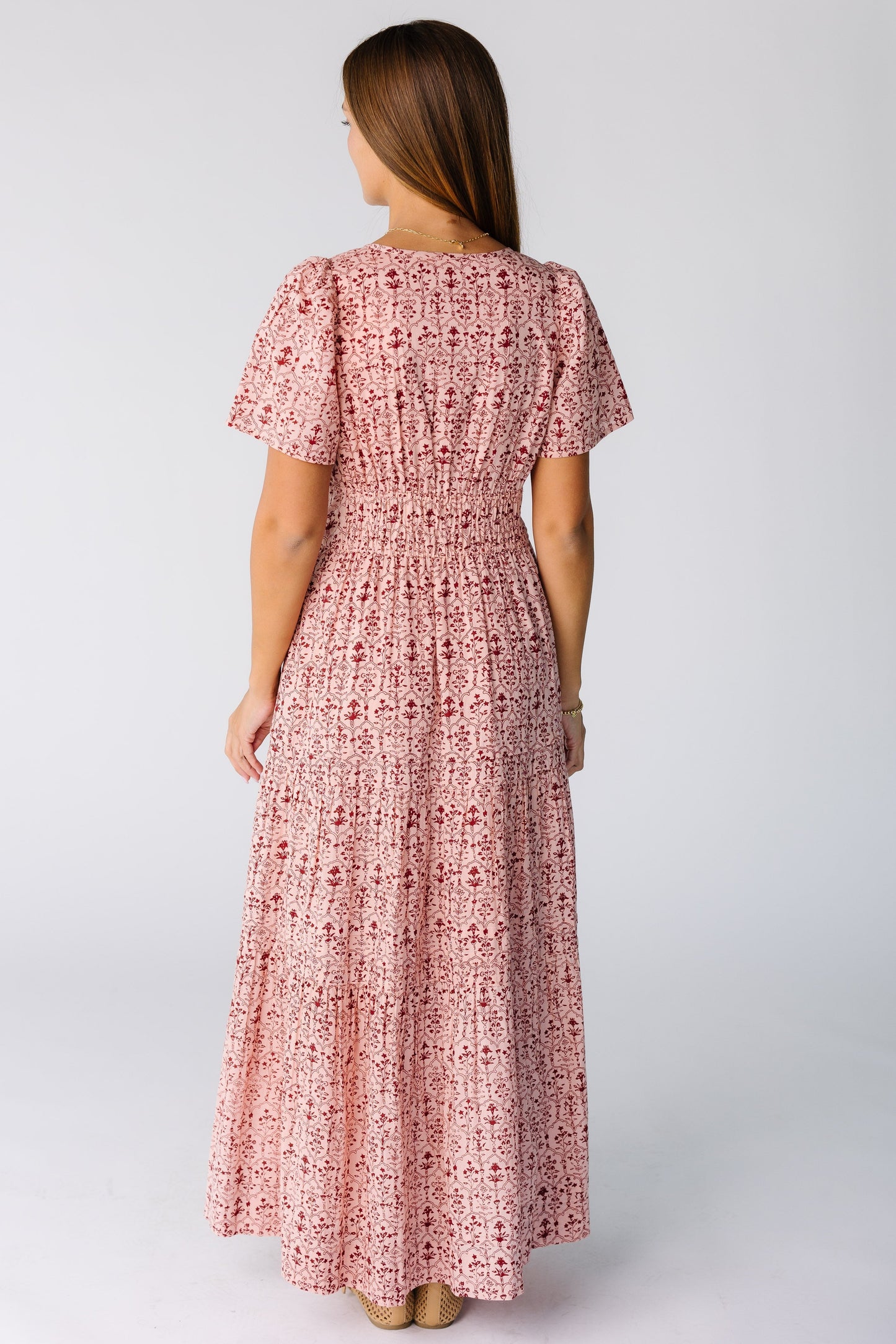 Back view of a woman wearing a pink print midi-maxi dress with short sleeves