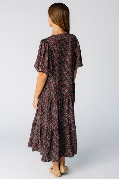 Back view of a woman wearing a black floral print midi dress with elbow length sleeves
