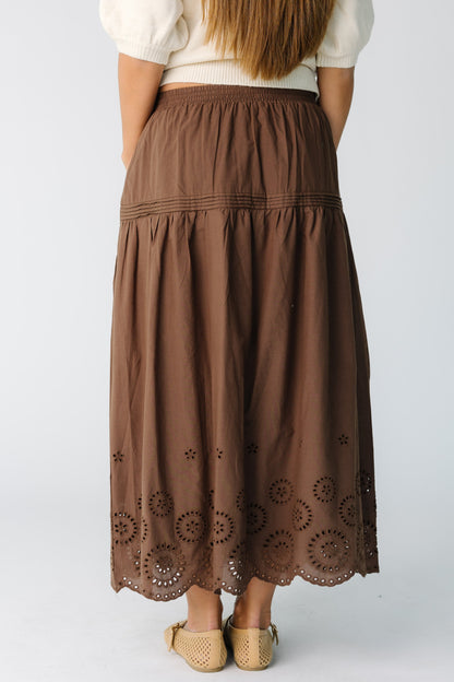Back view of a woman wearing a brown mdi skirt with eyelet hemline