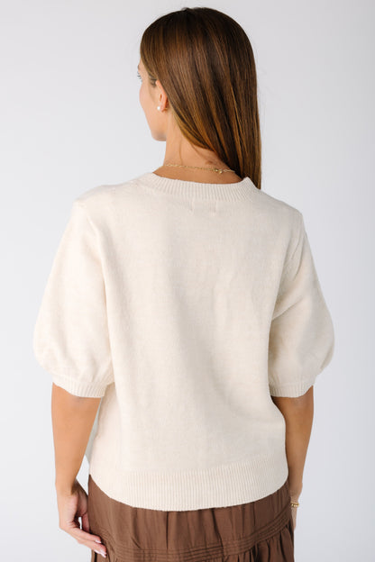 Back view of a woman wearing an ivory sweater with elbow length full sleeves