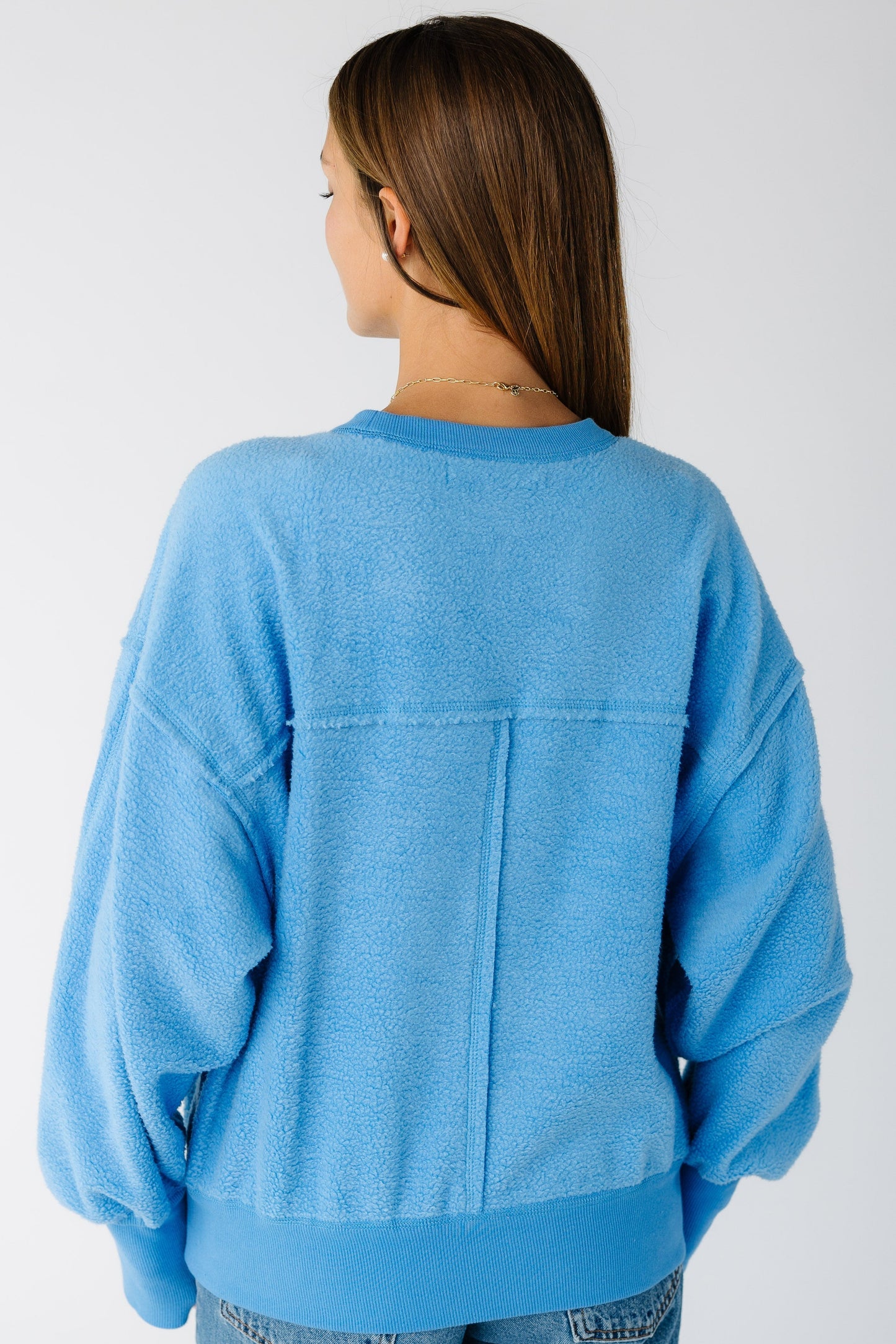 Back view of a woman wearing a blue loose fitting sweatshirt