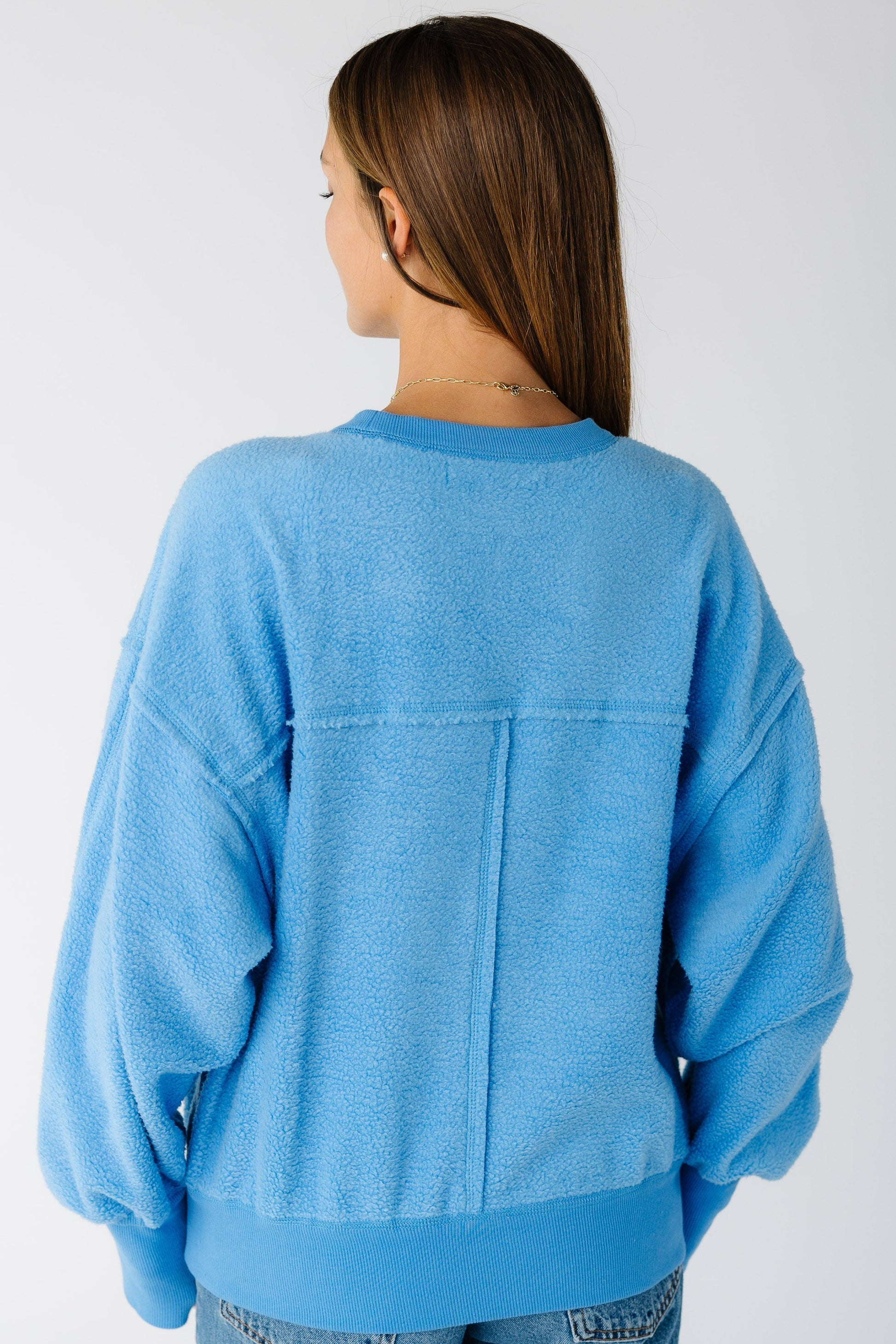 Back view of a woman wearing a blue loose fitting sweatshirt