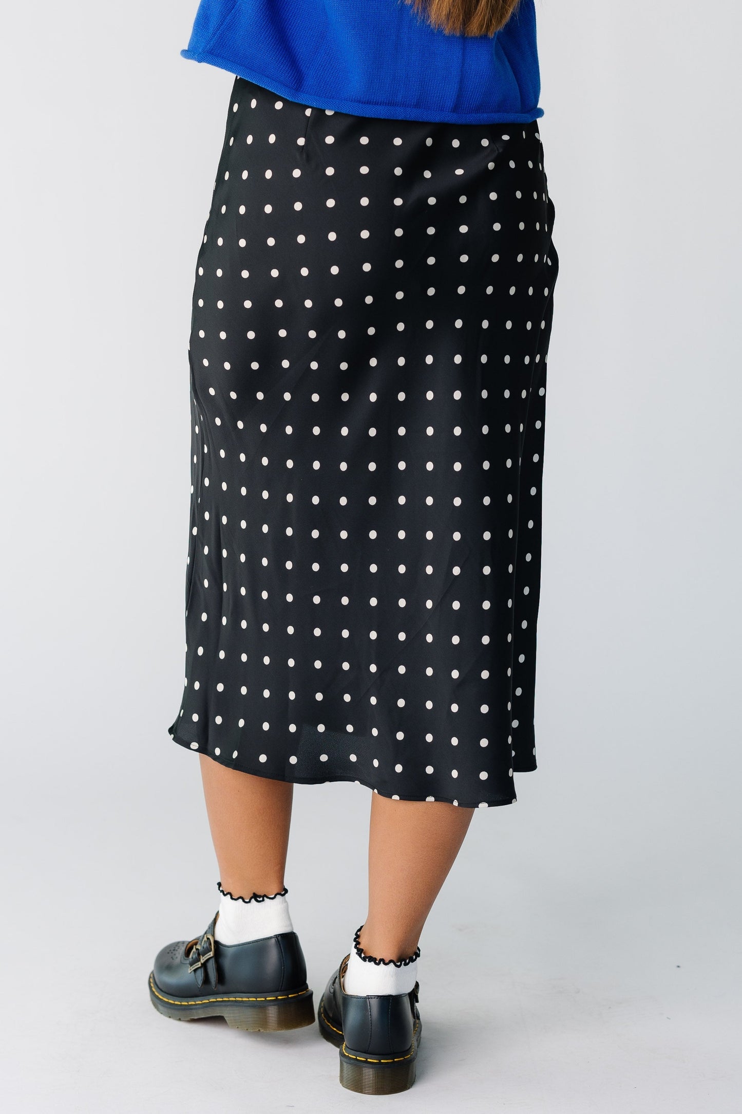 Back view of a woman wearing a black polka dot midi skirt