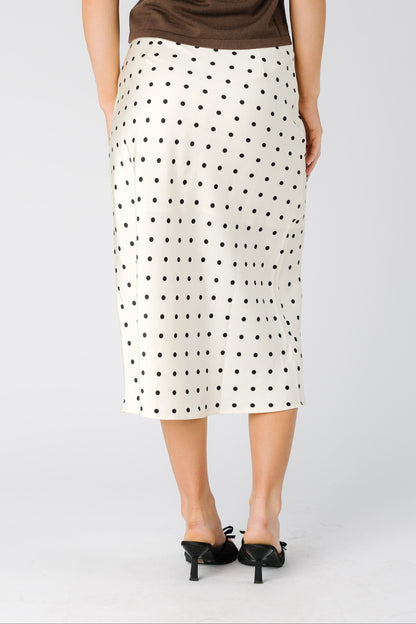 Back view of a woman wearing a cream polka dot midi skirt