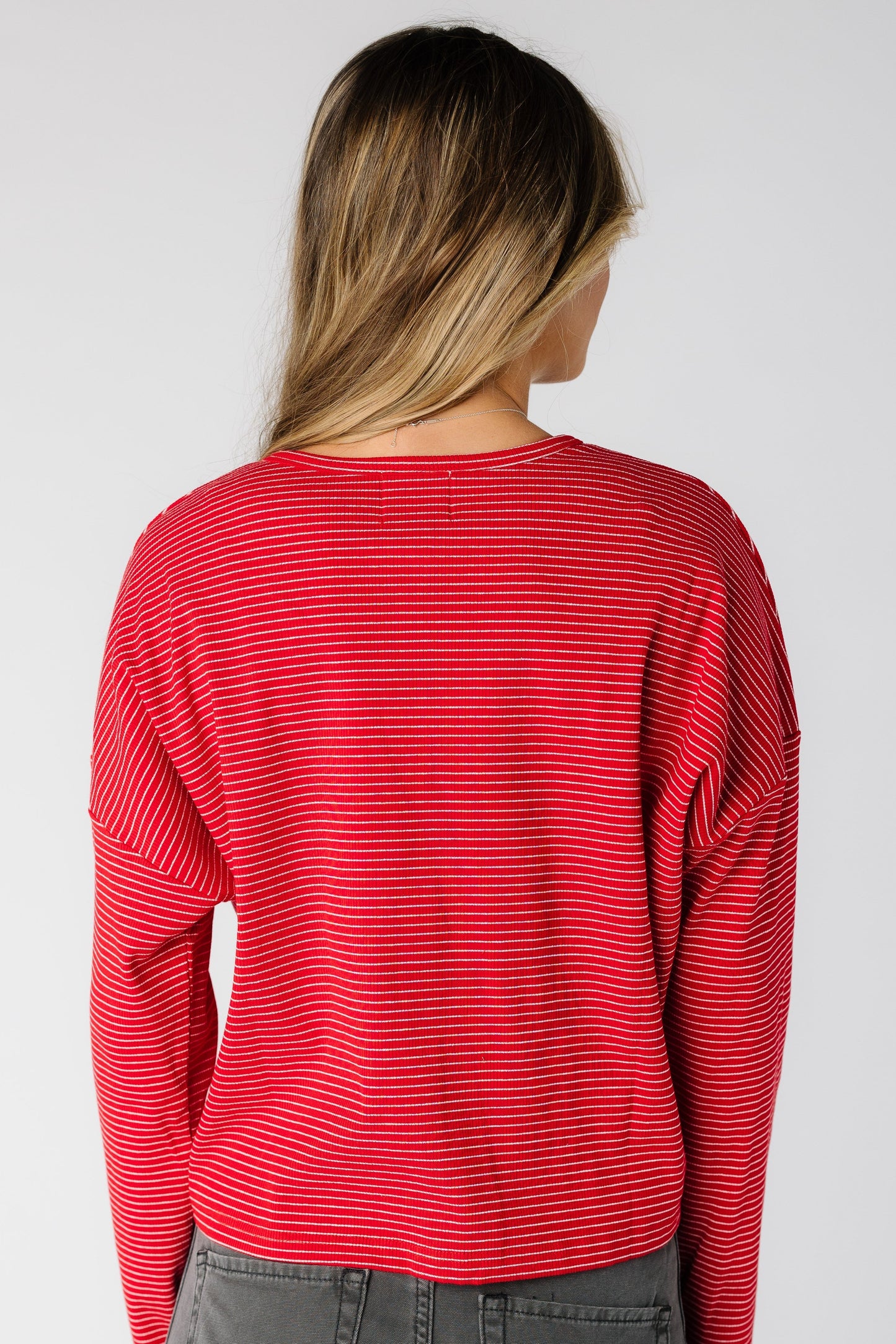 Back view of a woman wearing a  red pinstripe cardigan with long sleeves
