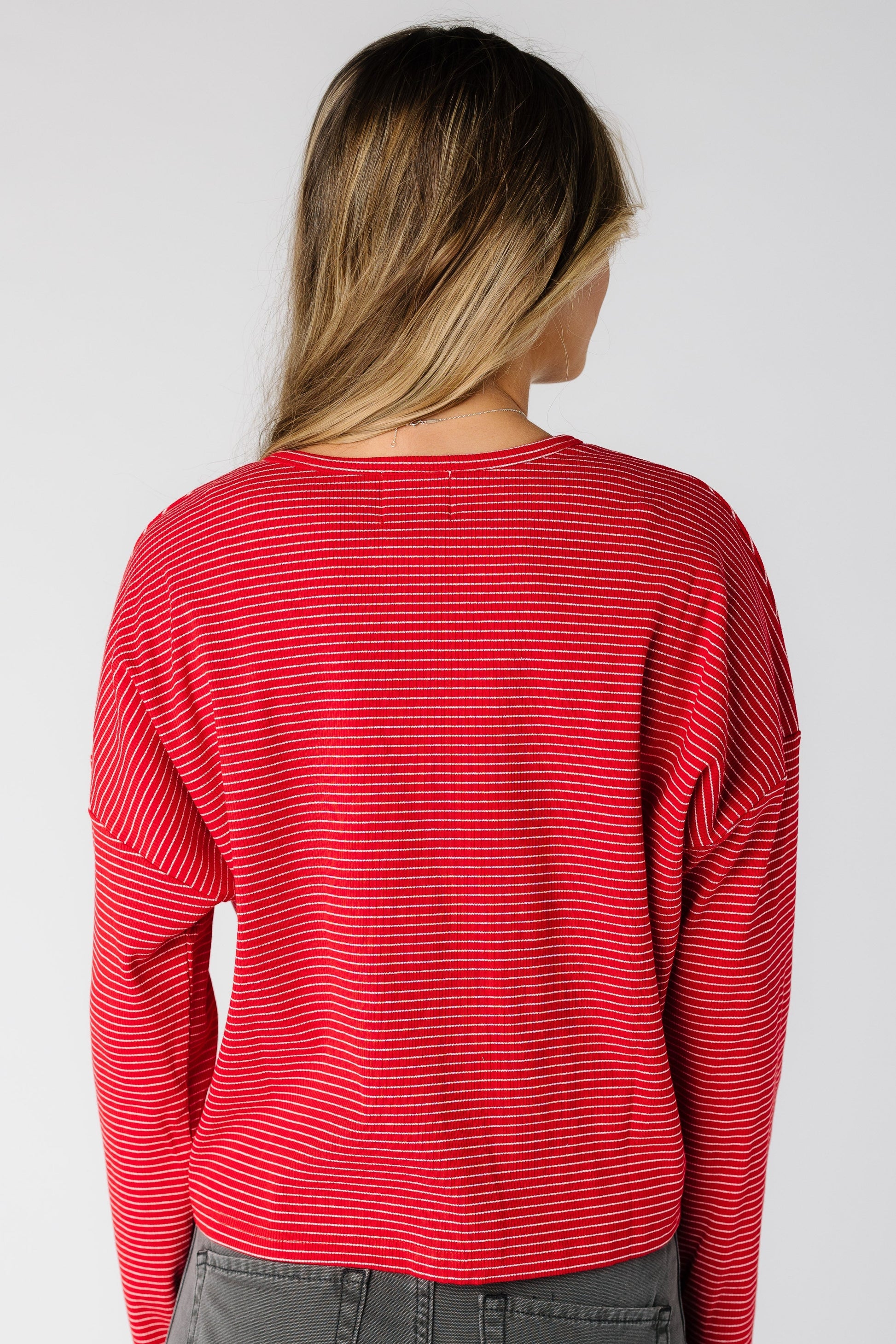 Back view of a woman wearing a  red pinstripe cardigan with long sleeves