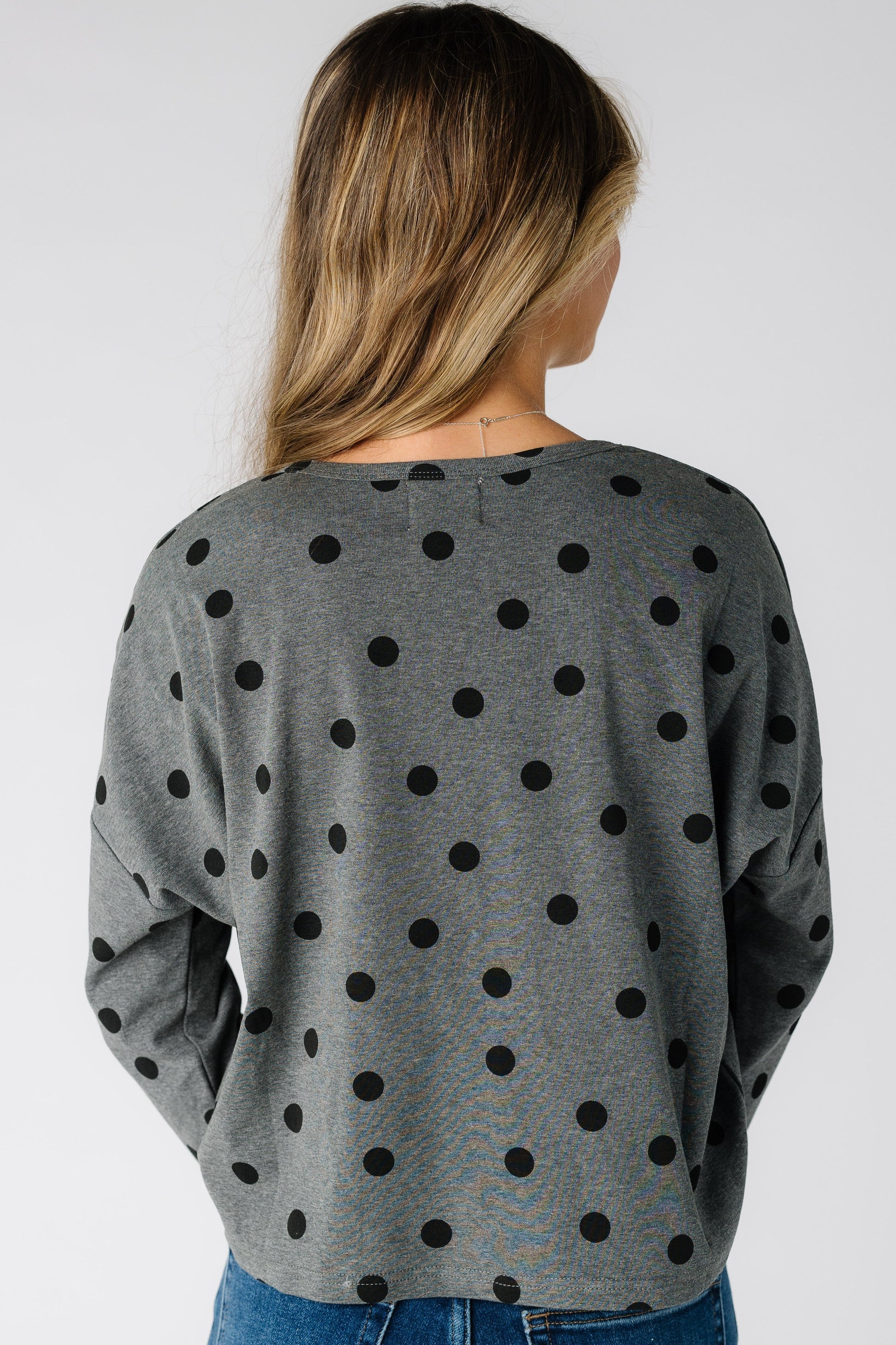 Back view of a woman wearing a grey cardigan with black polka dots