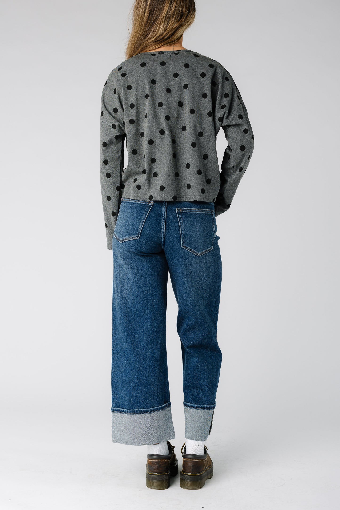 Back view of a woman wearing a pair of wide leg jeans with wide bottom cuffs