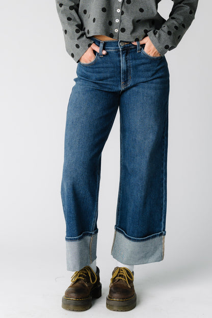 Woman wearing  pair of wide leg jeans in dark denim with wide cuffed hem