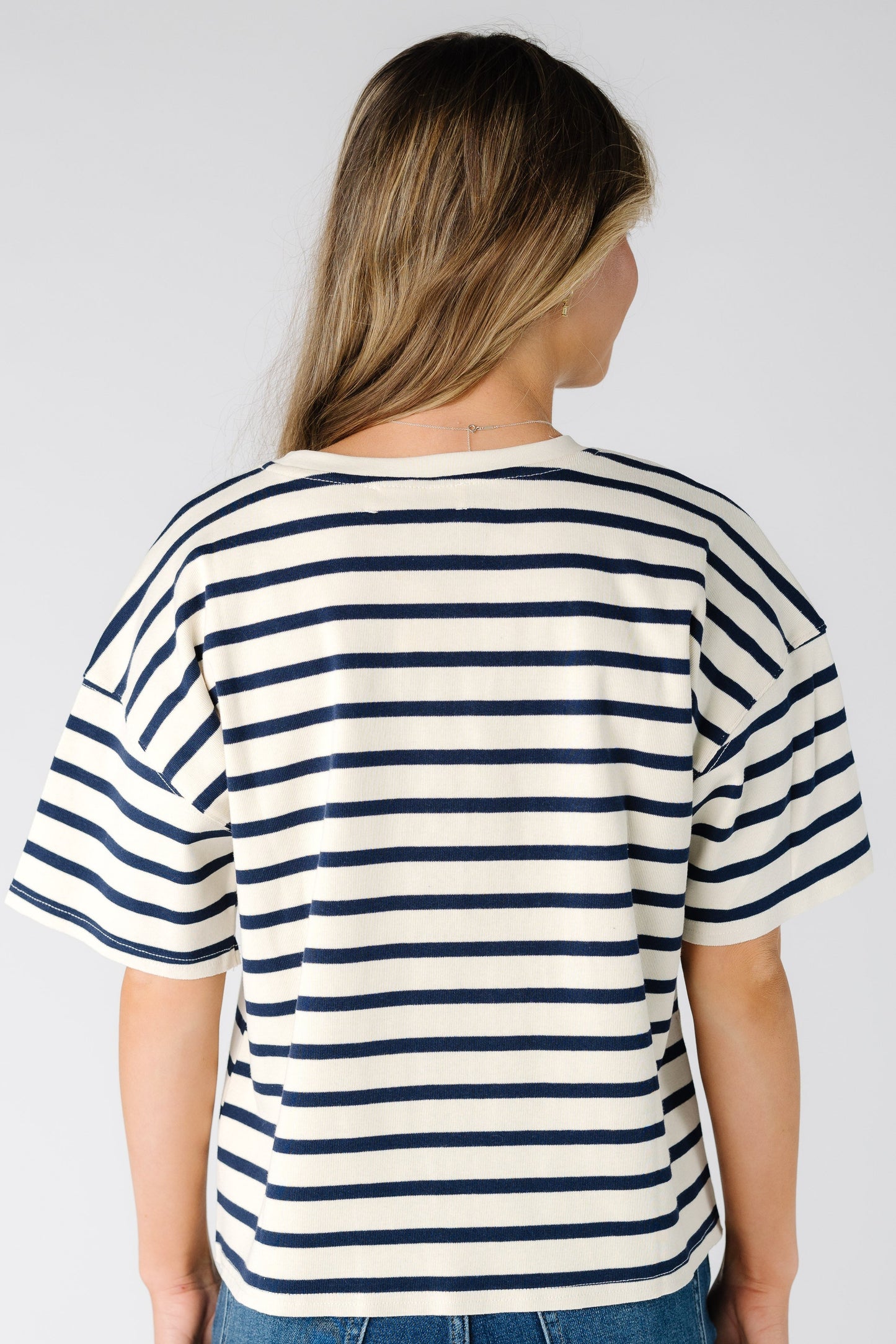 Back view of a woman wearing a white tee with black stripes and short sleeves.