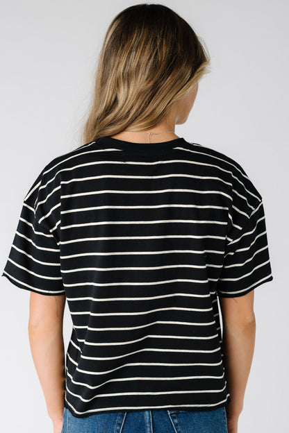 Back view of a woman wearing a black short sleeve tee with white stripes.