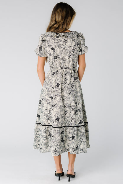 Back view of a woman wearing a black print dress with short sleeves