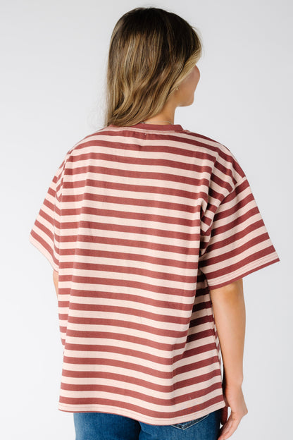 Back view of a woman wearing a blush and rust stripe tee with short sleeves
