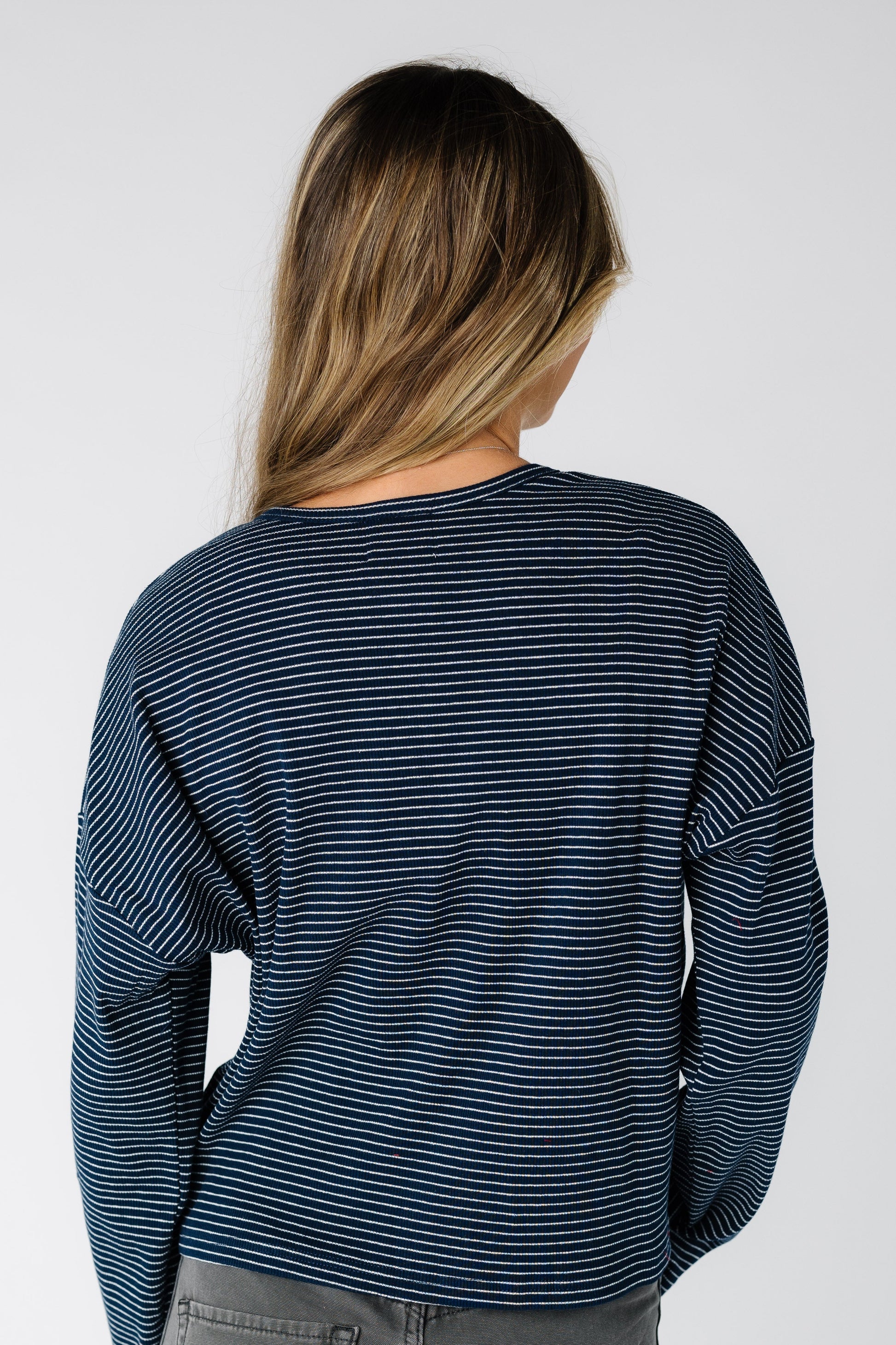 Back view of a woman wearing a navy pinstripe  cardigan with long sleeves
