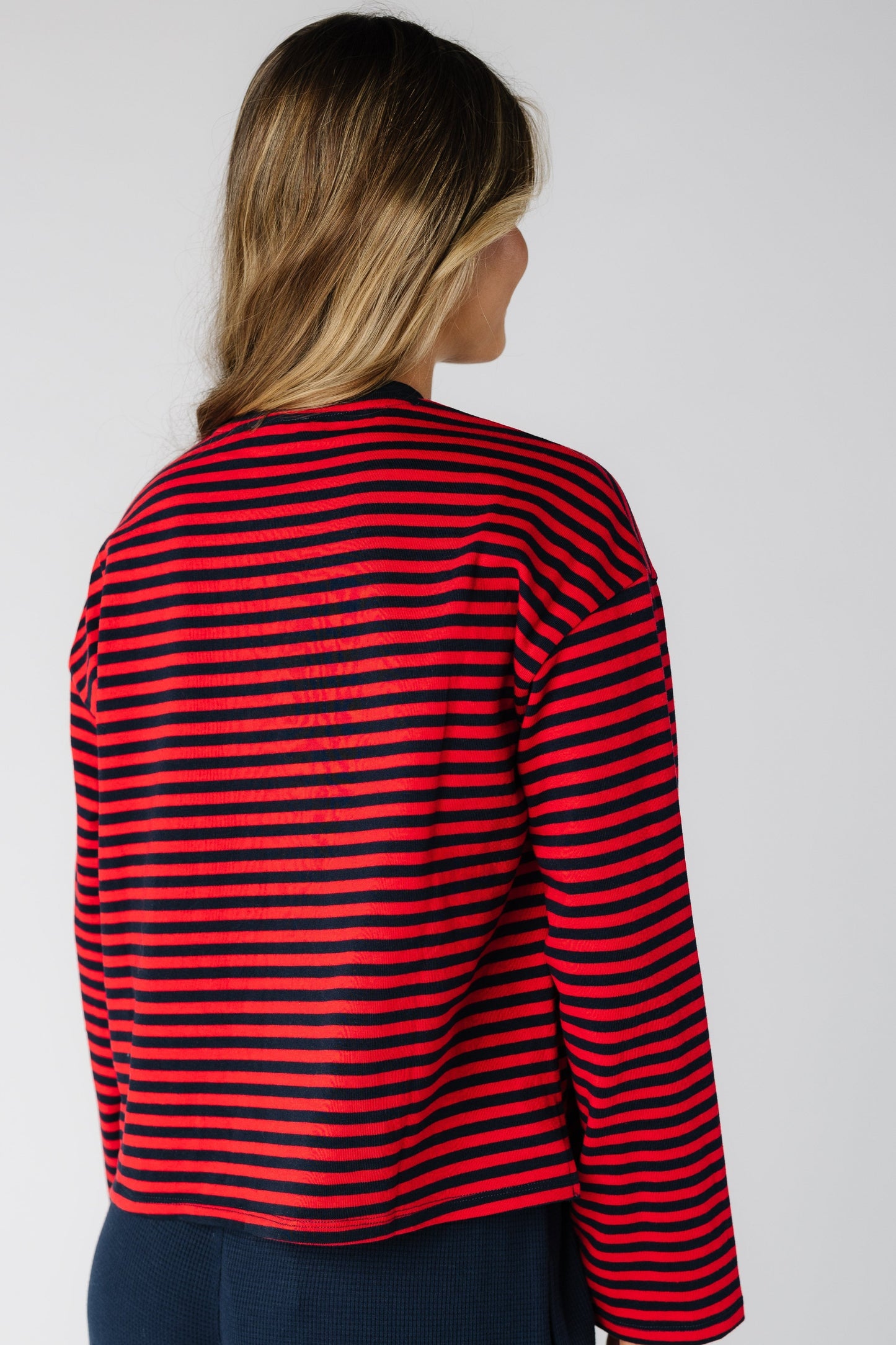 Back view of a woman wearing a loose fitting red and navy stripe long sleeve tee