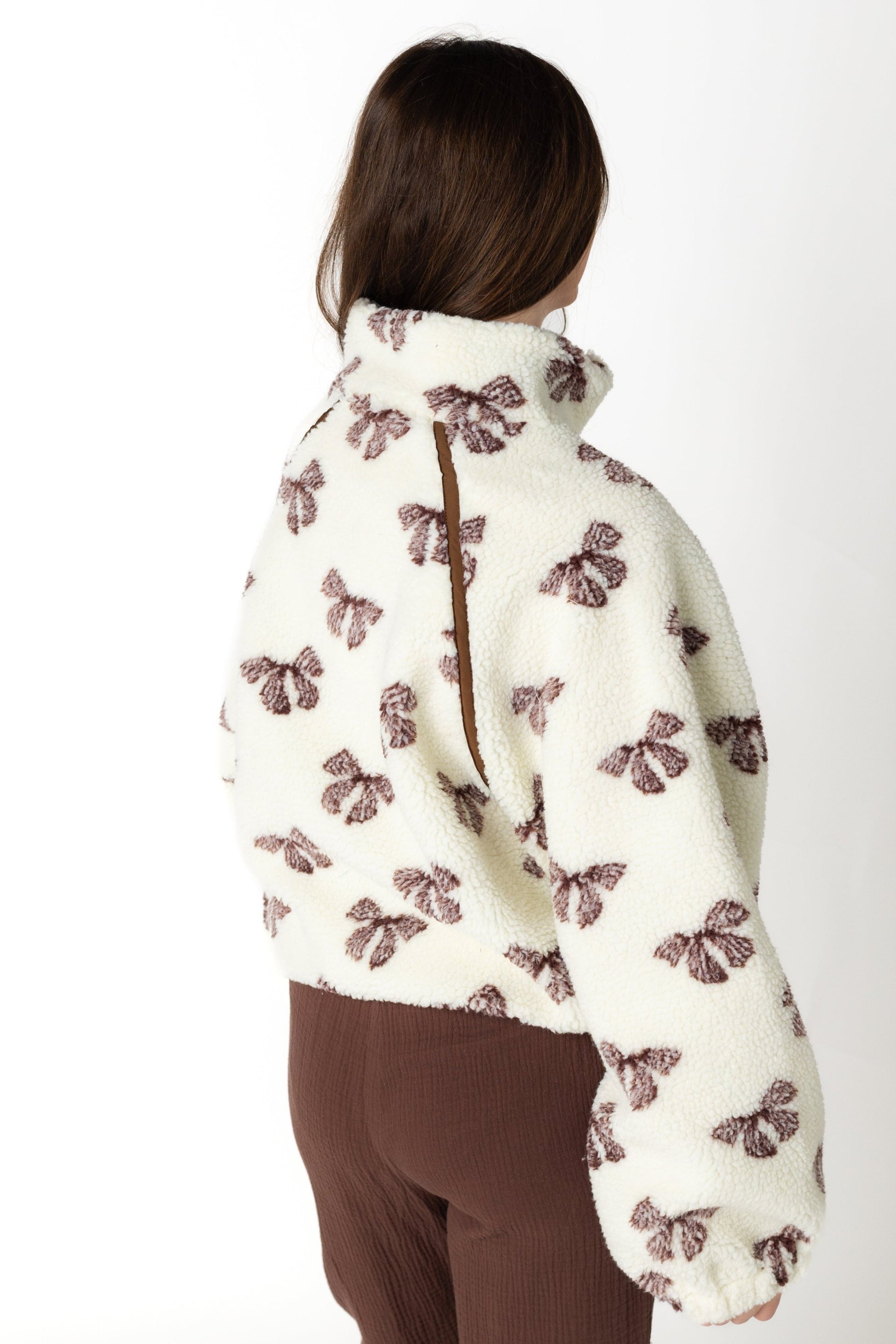 Back view of cream sherpa jacket with brown bow print