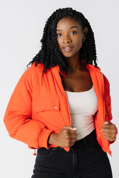 Orange puffy jacket with large front patch pockets and ribbed cuffs