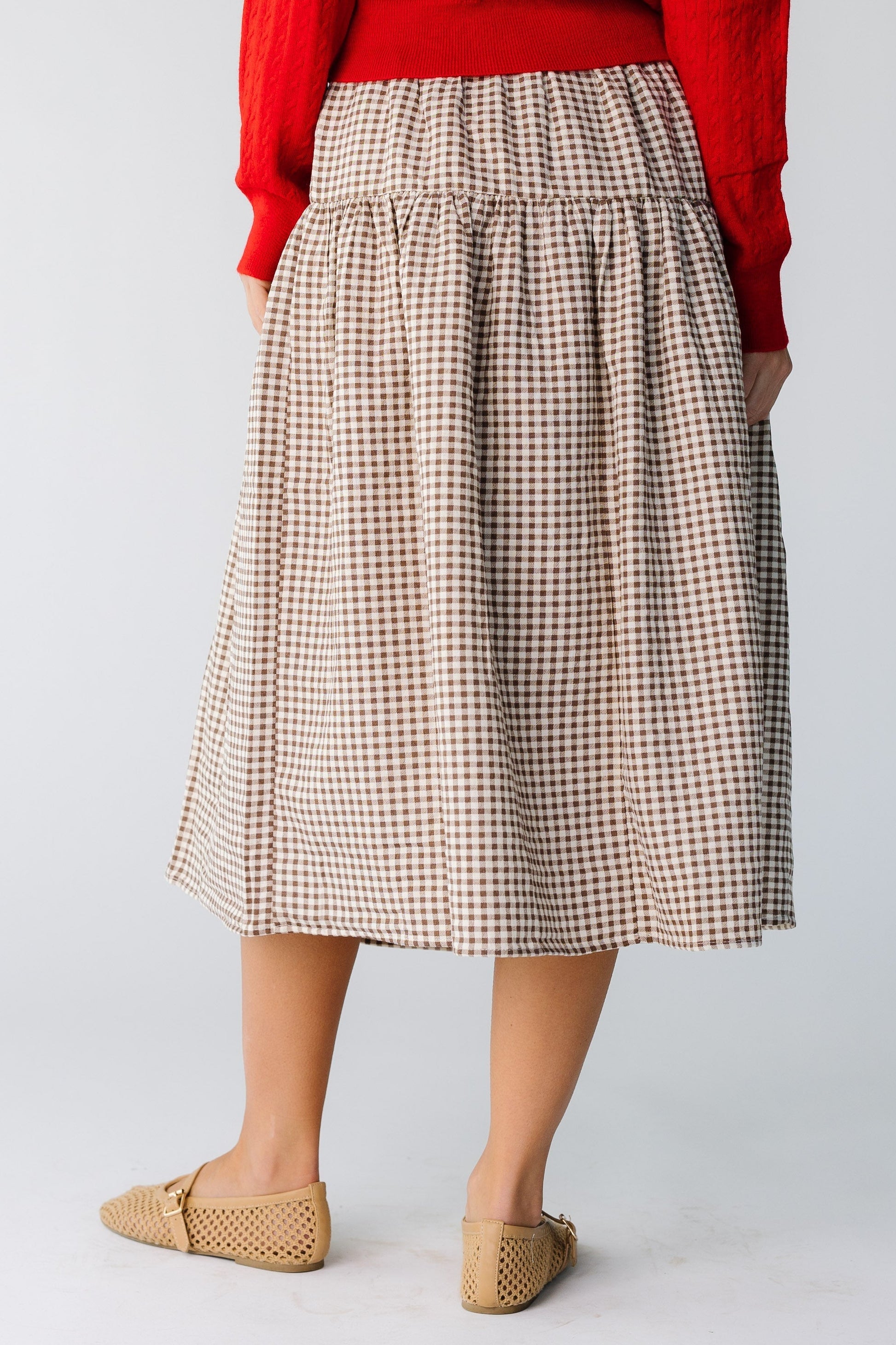 Back view of a woman wearing a brown gingham skirt