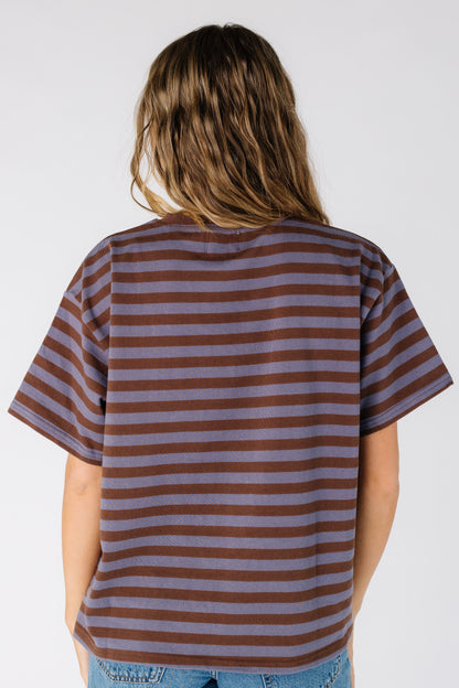 Back view of a woman wearing a loose fitting tee in dusty blue and brown 