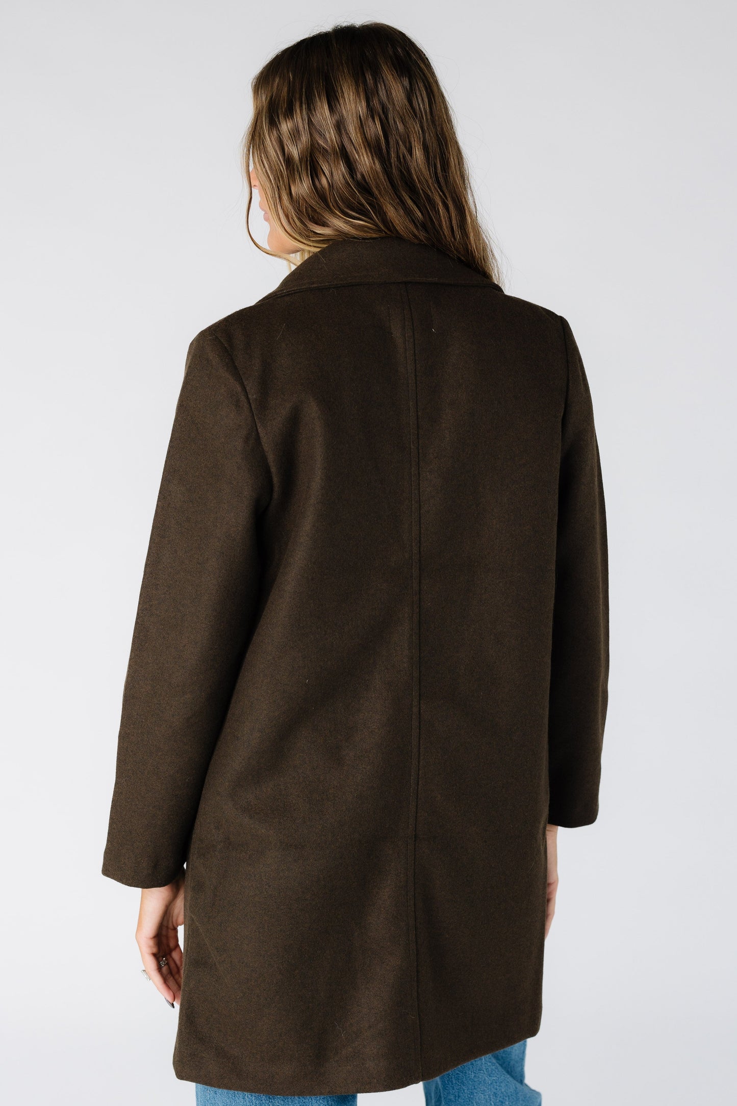 Back view of a woman wearing a dark brown coat with long sleeves