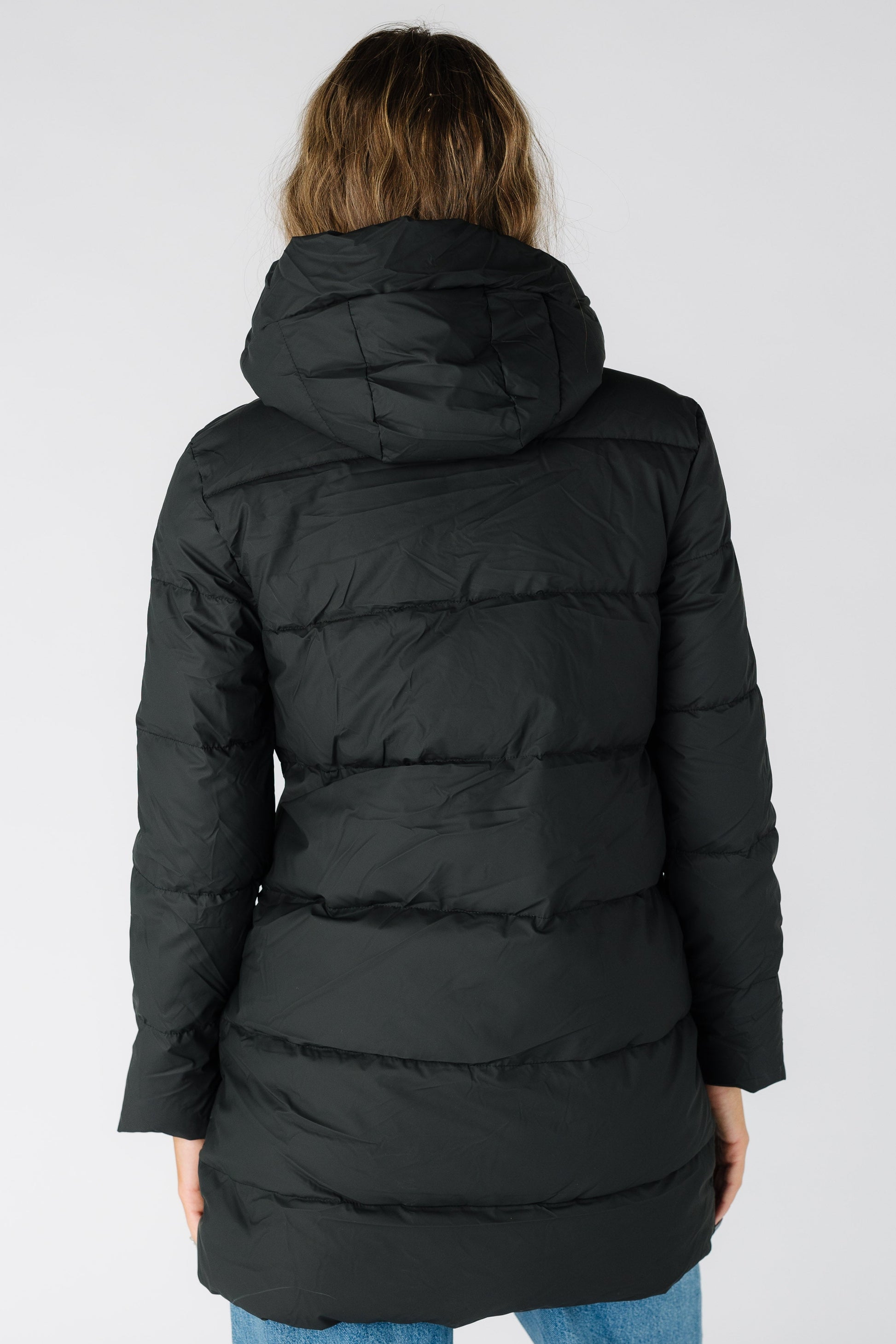Back view of a wearing black hooded puffer jacket with long sleeves