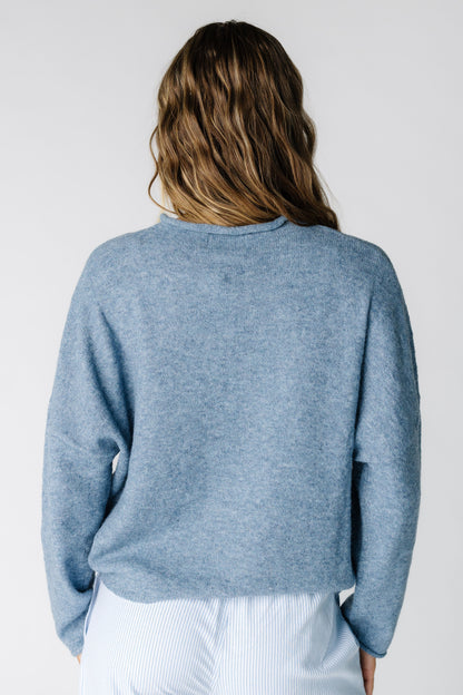 Back view of a woman wearing a dusty blue long sleeve sweater