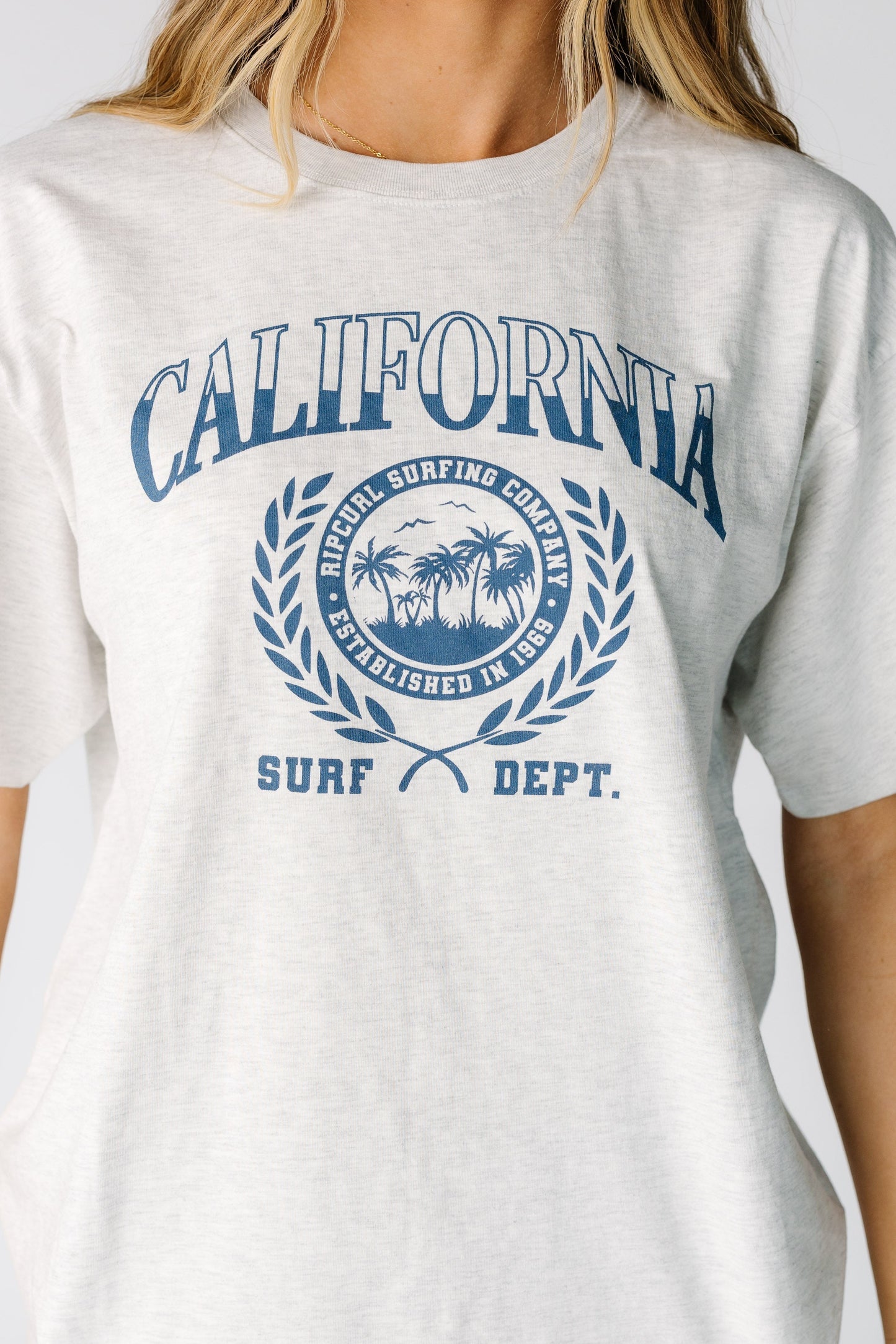 Close view of a woman wearing a large blue graphic on a light grey short sleeve tee