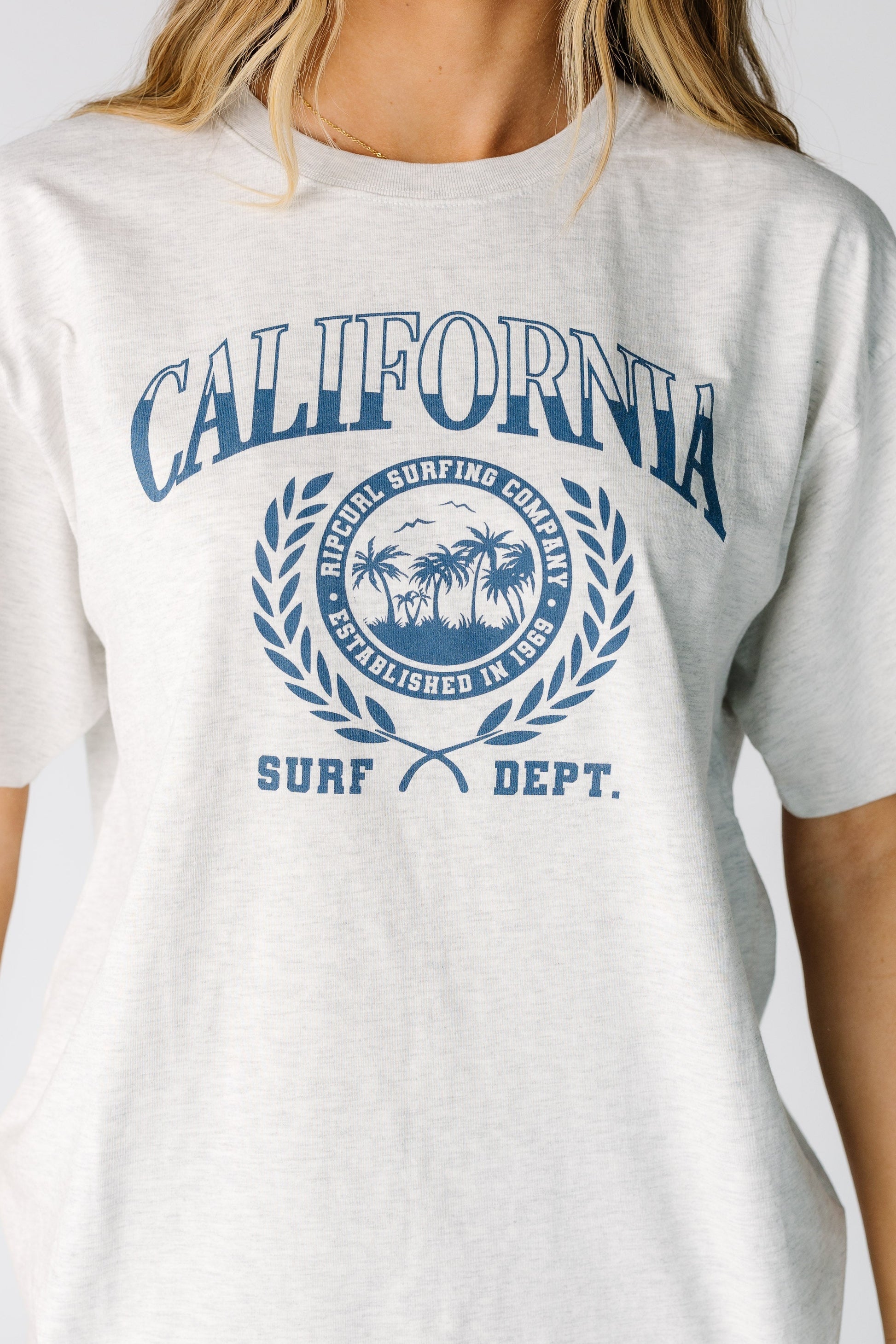 Close view of a woman wearing a large blue graphic on a light grey short sleeve tee