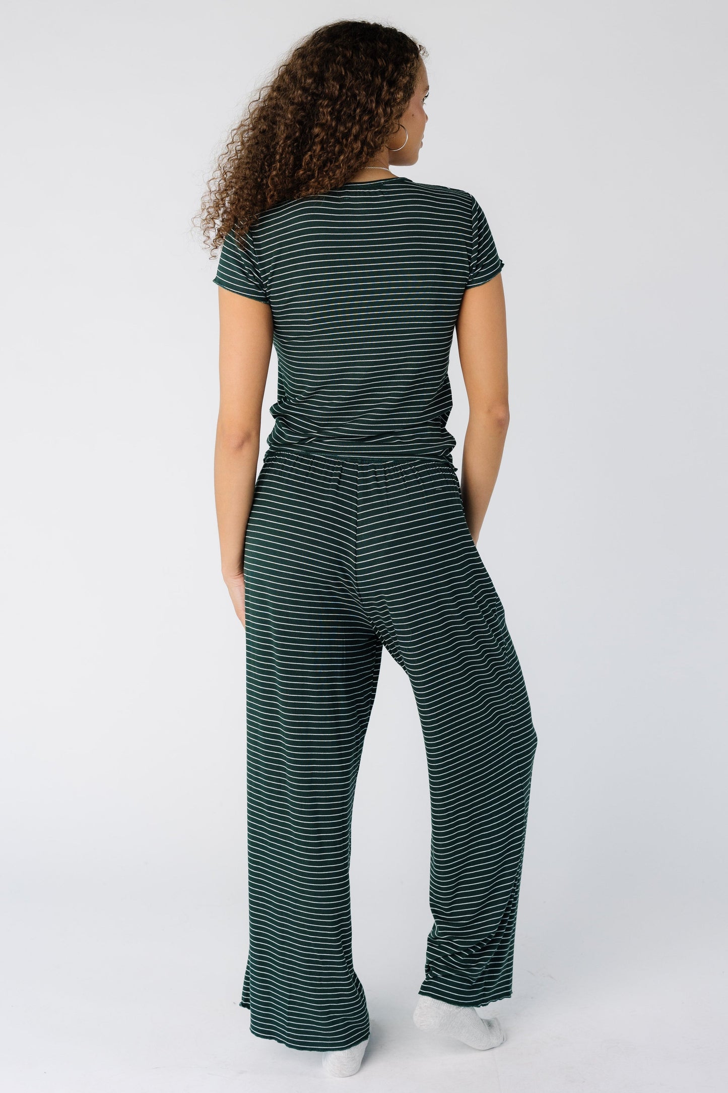 Back view of a woman wearing a green stripe pajama lounge set