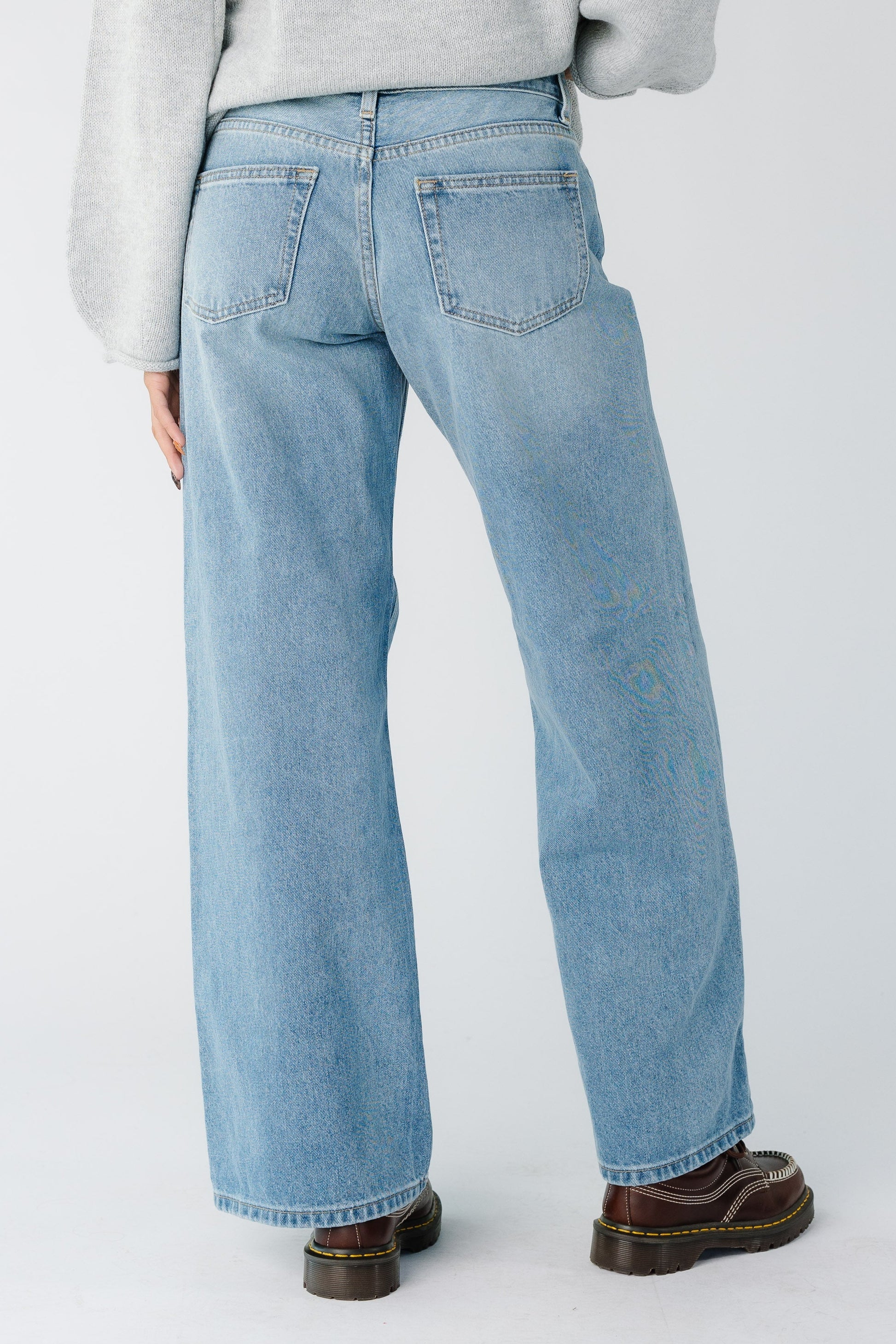 Back view of a woman wearing a pair of wide leg baggy jeans in medium denim