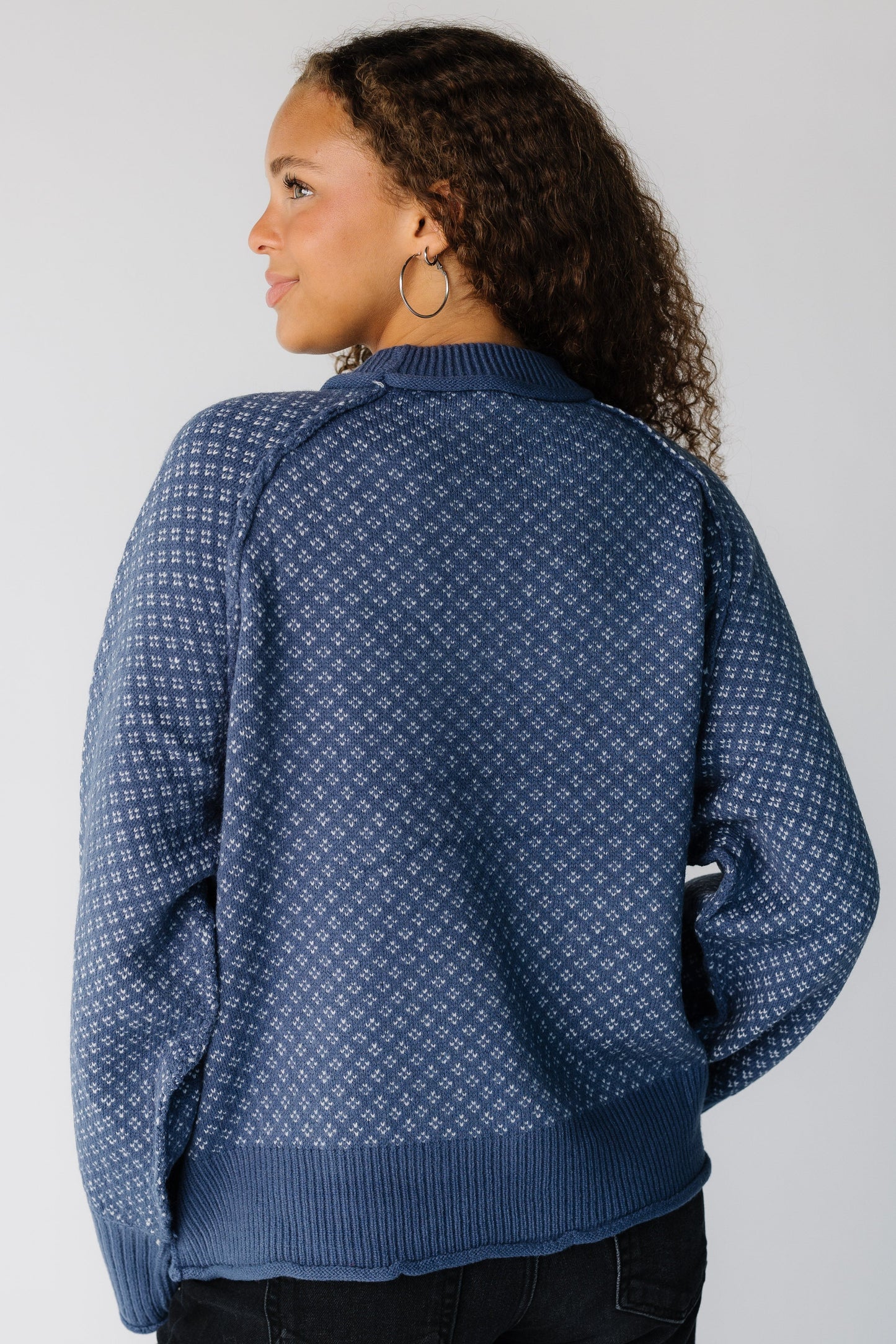 Back view of a teen girl wearing a blue patterned pullover sweater