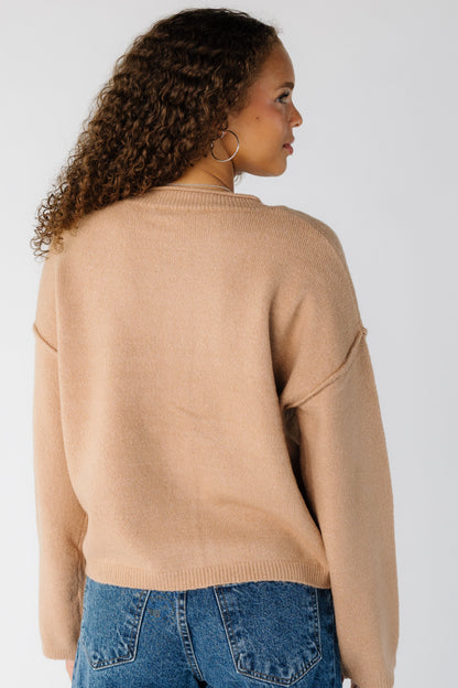 Back view of a woman wearing a taupe long sleeve sweater with drop shoulders and exposed sleeves