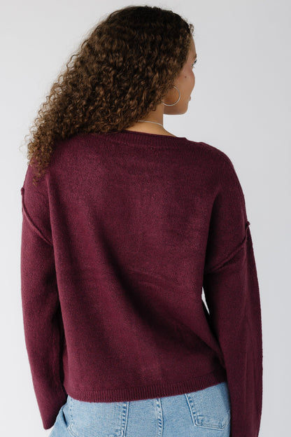 Back view of a woman wearing a cark cherry cardigan with long sleeves