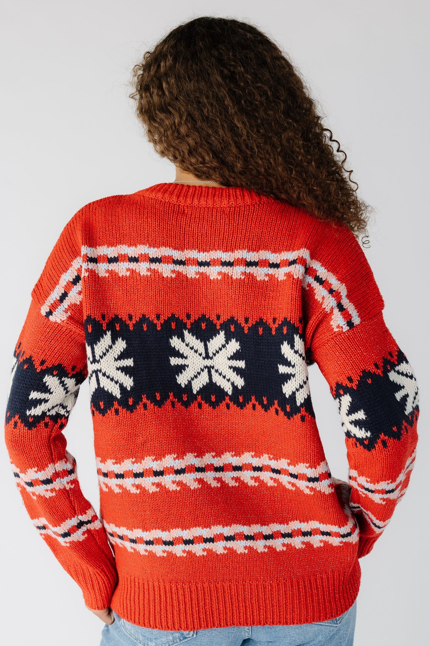 Back view of a woman wearing a long sleeve red sweater with a snowflake graphic
