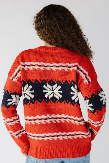 Back view of a woman wearing a long sleeve red sweater with a snowflake graphic