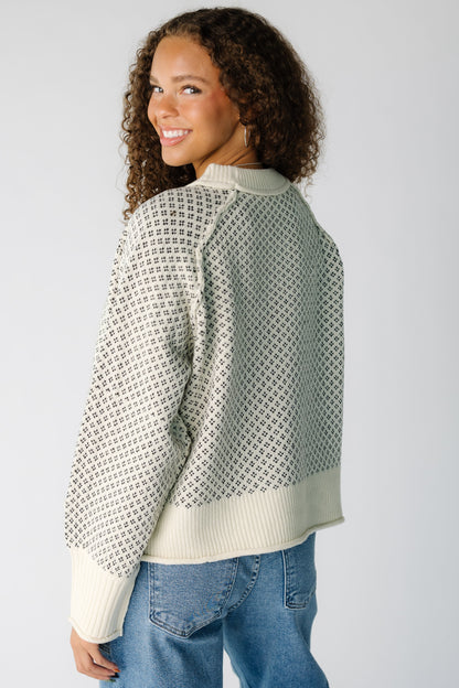 Back view of a teen girl wearing a cream & black patterned pullover sweater with long raglan sleeves