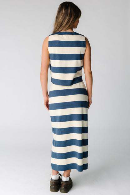 Back view of a woman wearing a blue and cream wide stripe skirt and top set with a midi skirt and sleeveless top.