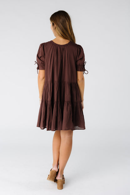 Back view of a woman wearing a brown loose fitting dress with short sleeves
