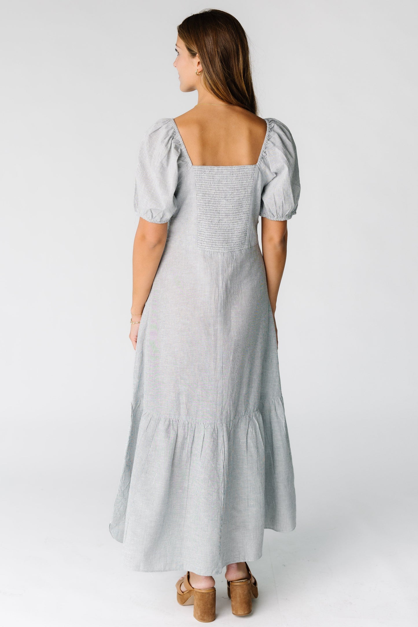 Back view of a woman wearing a navy stripe maxi dress with a square neckline and smocked back bodice