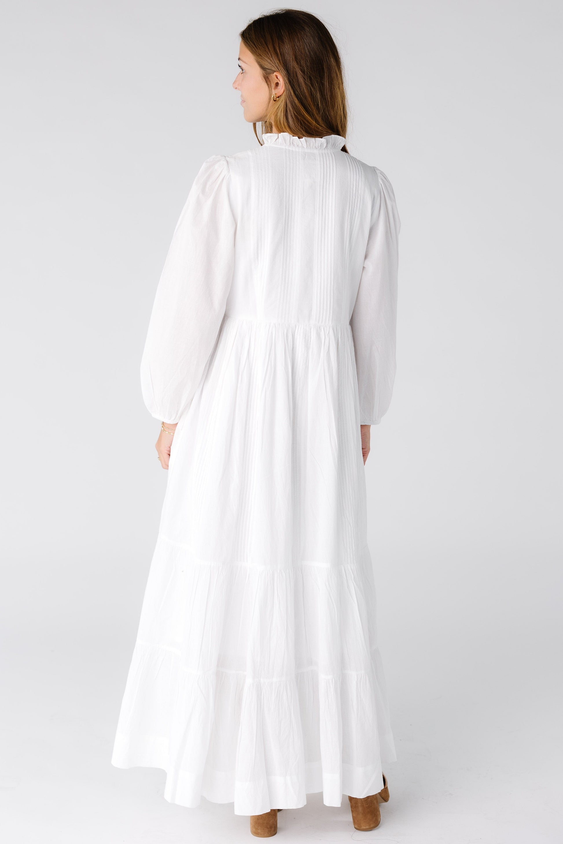 Back view of a woman wearing a white maxi dress with long sleeves