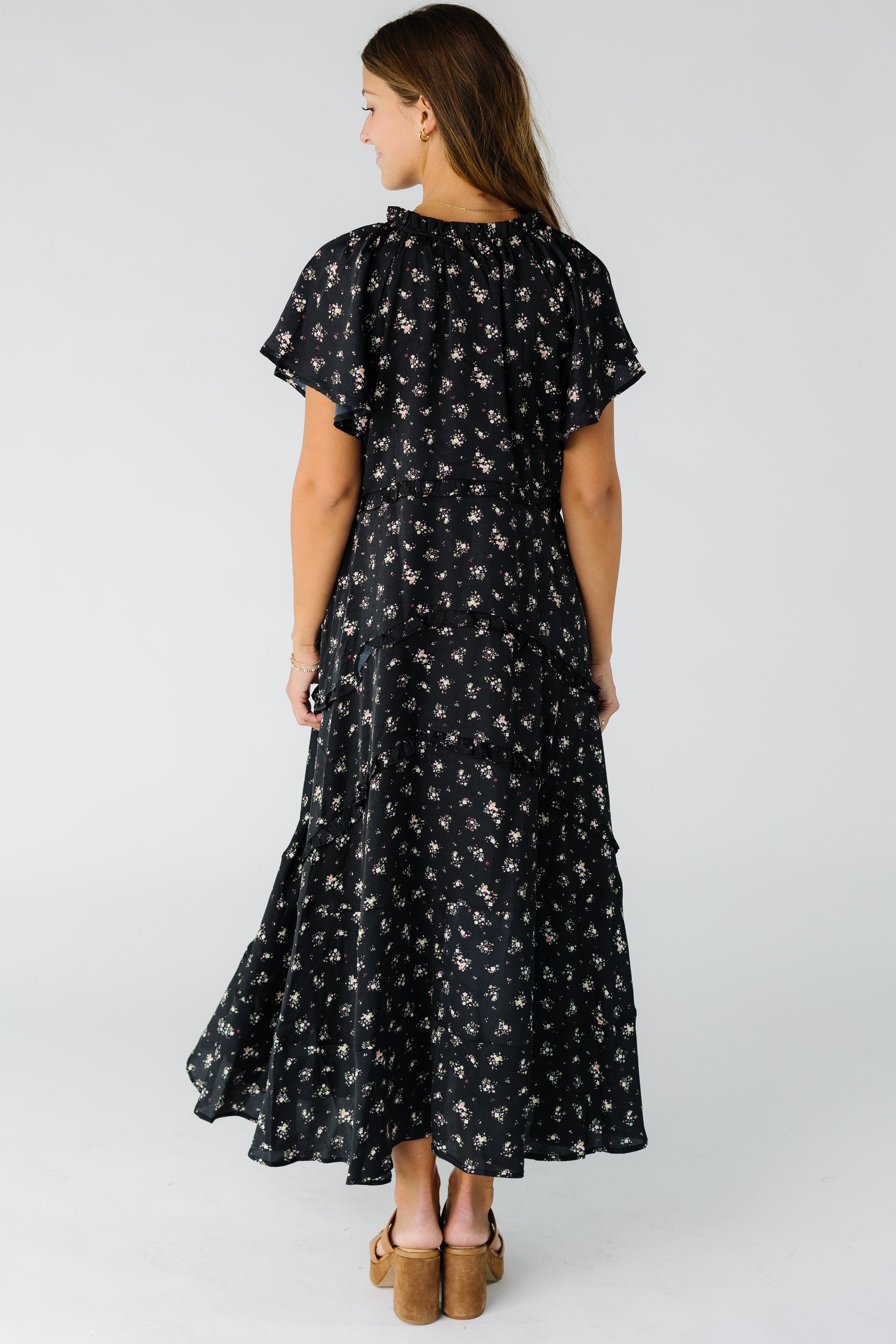 Back view of a woman wearing a black floral maxi dress with short sleeves