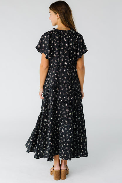 Back view of a woman wearing a black floral maxi dress with short sleeves